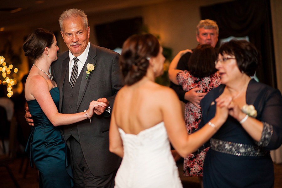 Father of the bride looking at mother and bride dancing