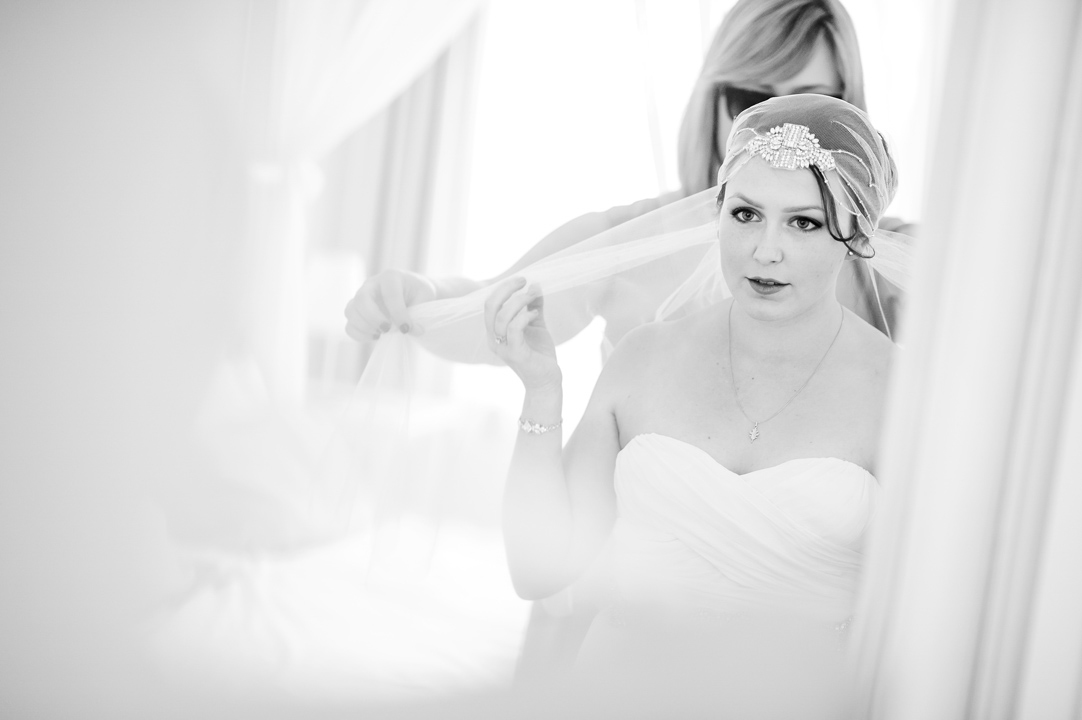 Wedding guest helps bride put her veil on.