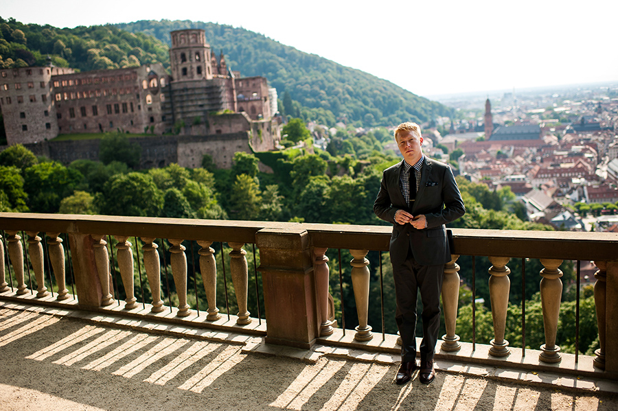 Groom fixes his jacket with Heidelberg castle in background on his wedding day