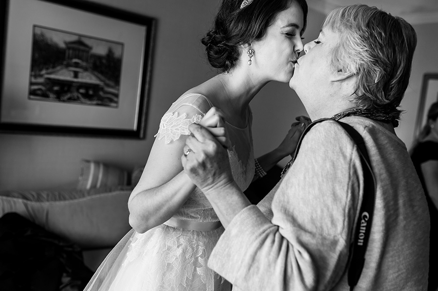 Mother and bride kissing before wedding ceremony.