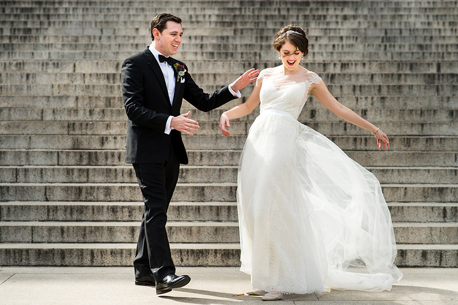 Bride's dress flying in the wind as groom helps.