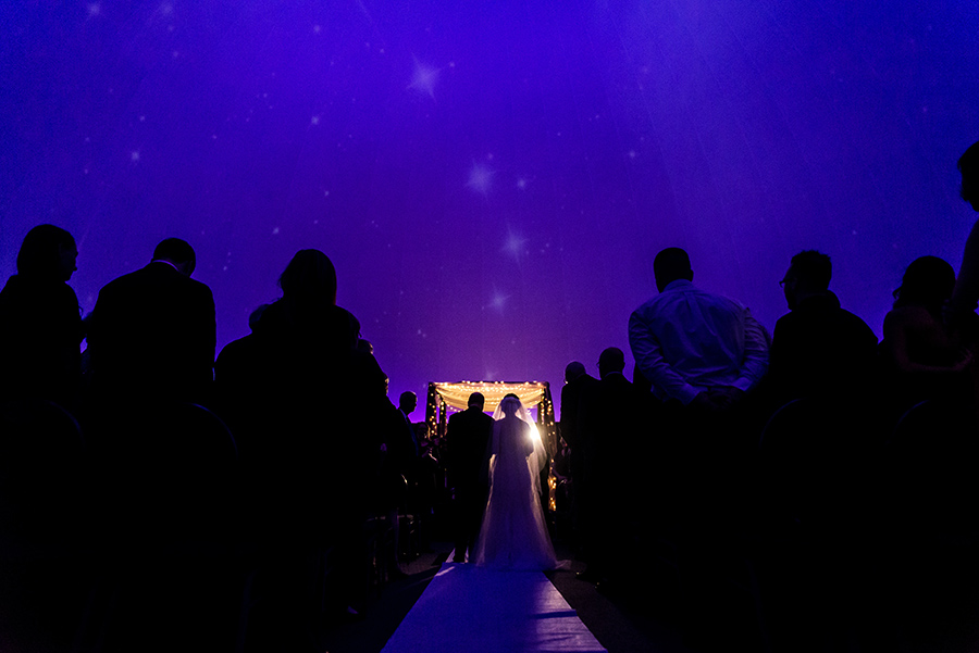 Father of the bride and bride walking down the aisle at wedding ceremony in Planetarium in Franklin Institute.
