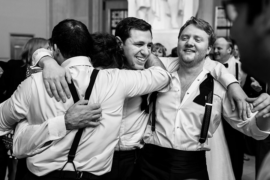 Groom hugging groomsmen during wedding reception.