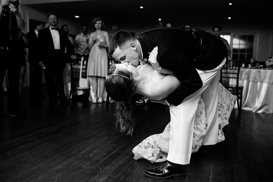 Groom dips bride during dancing at wedding reception.