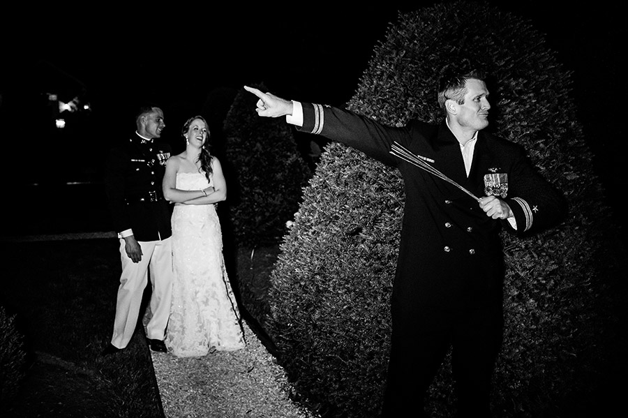 Groomsmen directs wedding guests inside as bride and groom laugh.