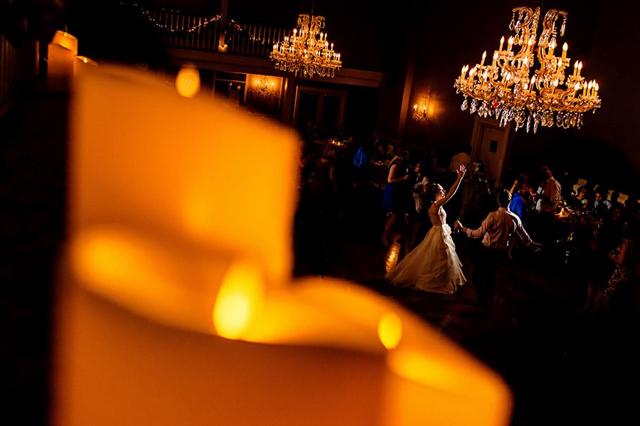 Wide shot of bride dancing on the dance floor with candles in the foreground.