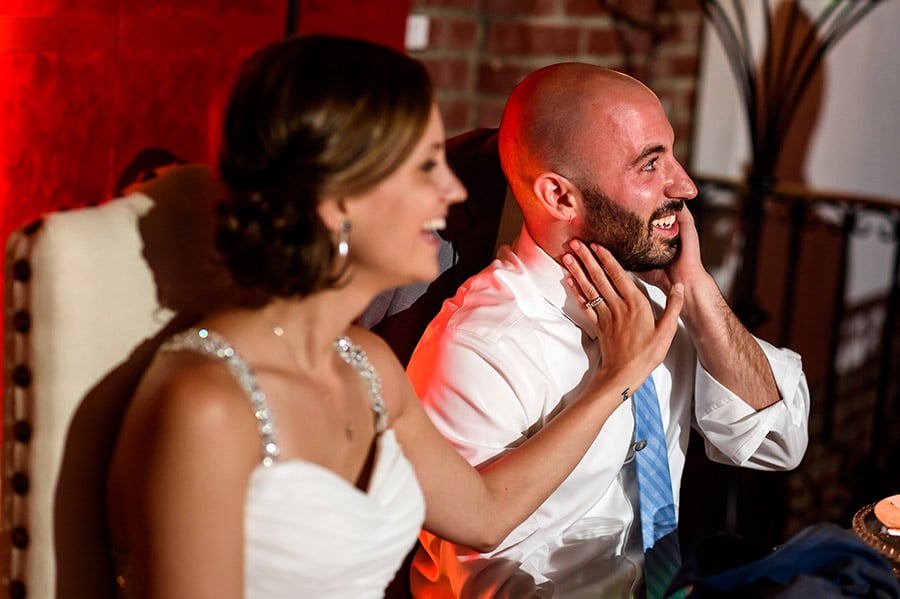 Bride touches groom on the face during wedding speeches