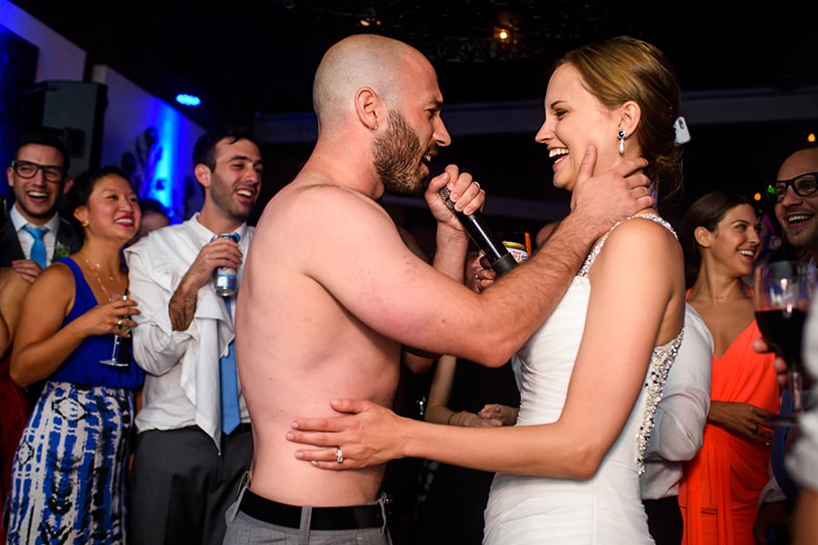 Shirtless groom sings to bride during wedding reception.