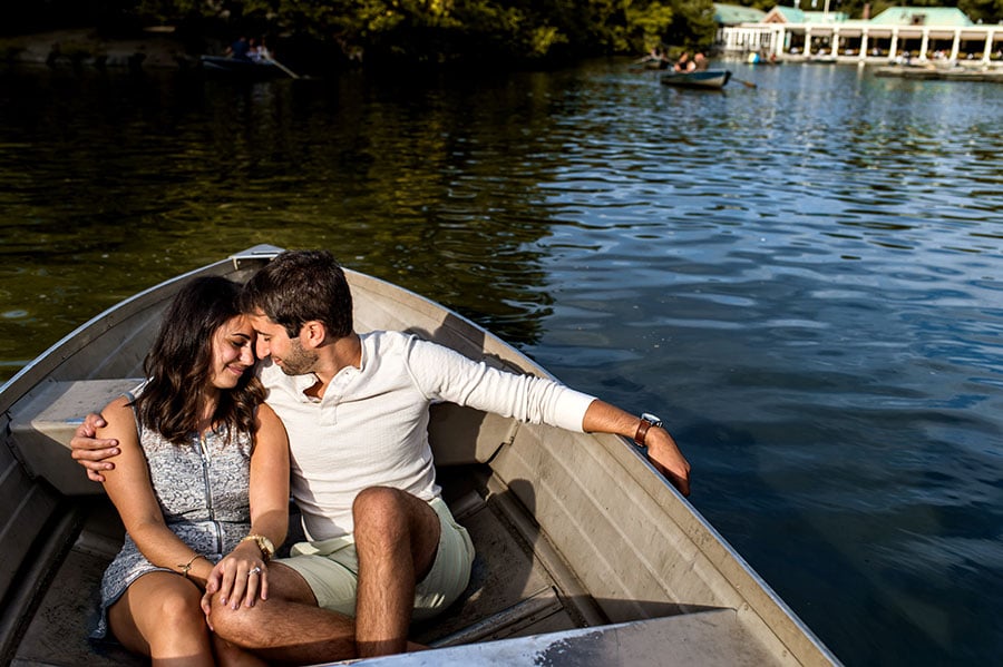 An engaged couple sit in a boat in Central Park during their engagement session.