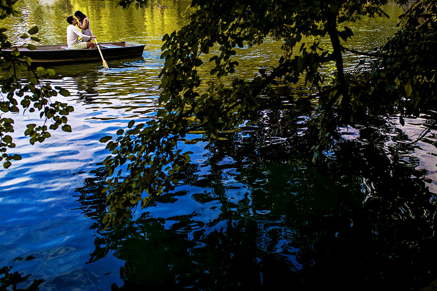 Woman kissed man in a boat on Central Park's lake during their engagement session.