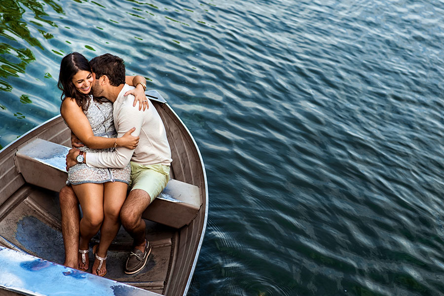 An engaged couple sit in a boat in Central Park during their engagement session.