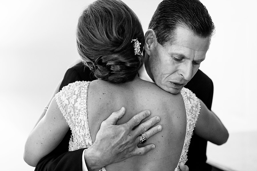 Father of the bride hugging his daughter for the first time in her wedding dress.