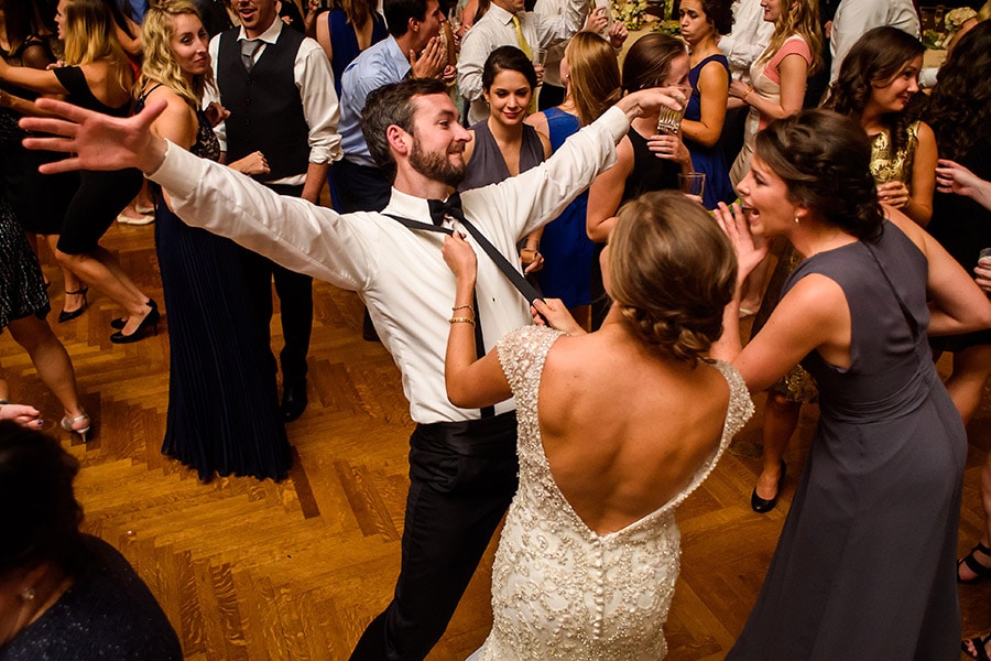 Bride dancing and pulling on groomsmen's suspenders during wedding reception!