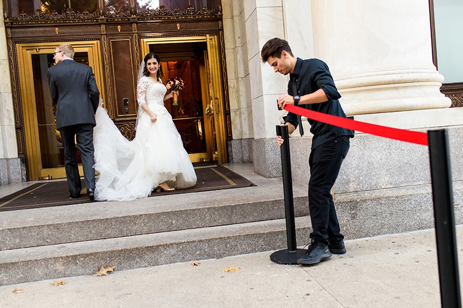 Bride and groom enter the Downtown Club as parking attendant puts out red tape.