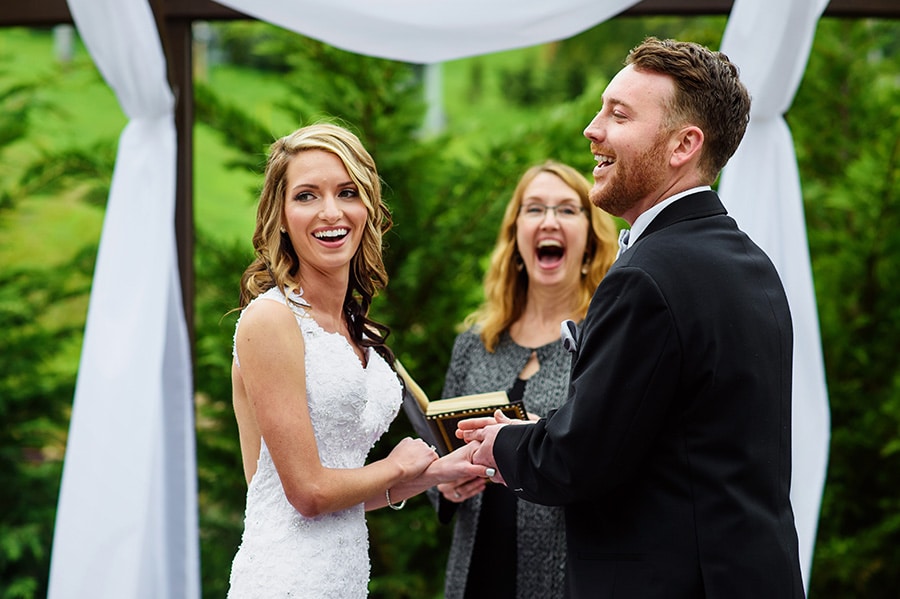 Bride, groom and officiant laugh during wedding ceremony at Bear Creek Mountain Resort.